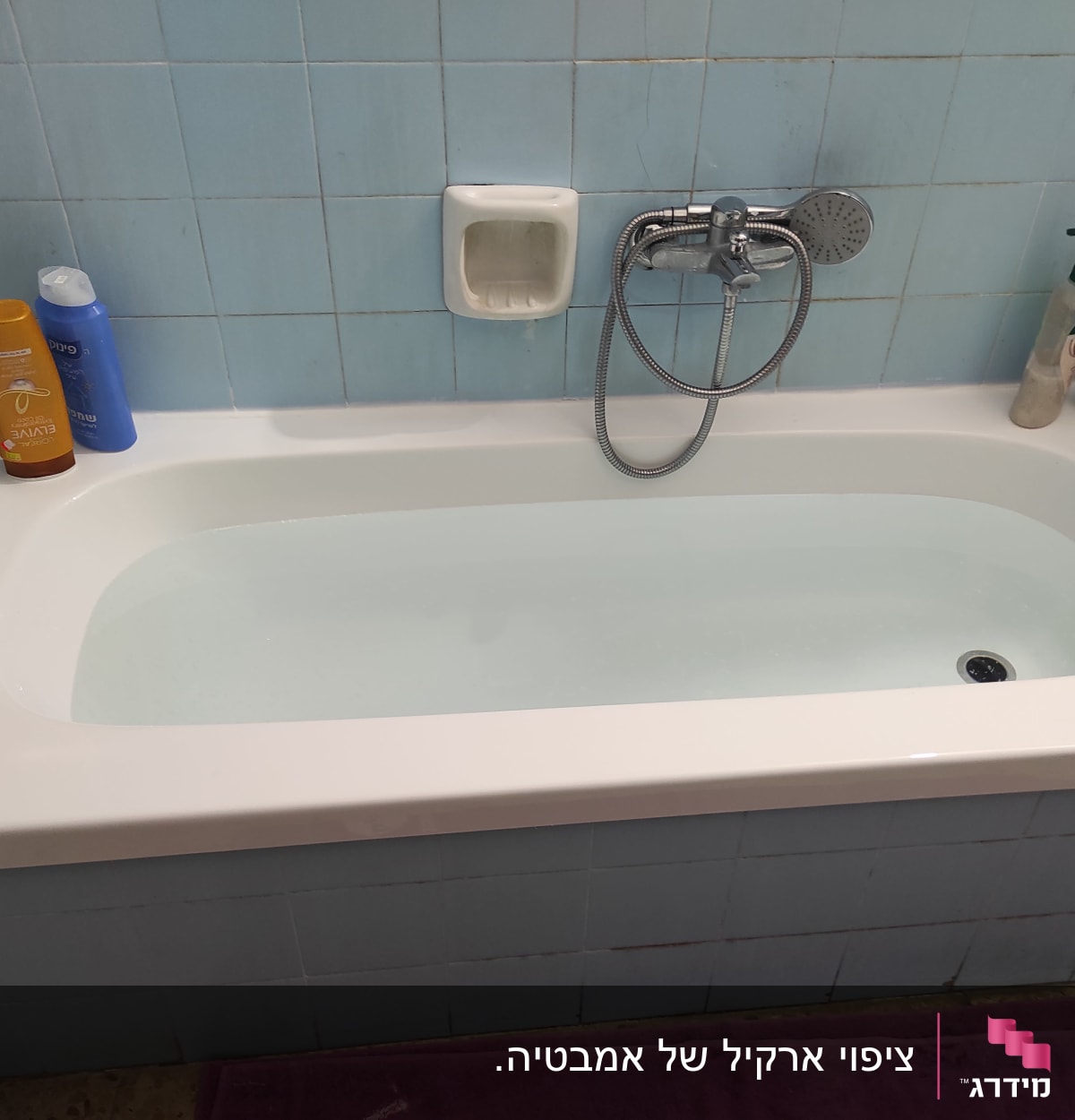 אמבטיה עם אריחים כחולים, ברז ומוצרי טיפוח